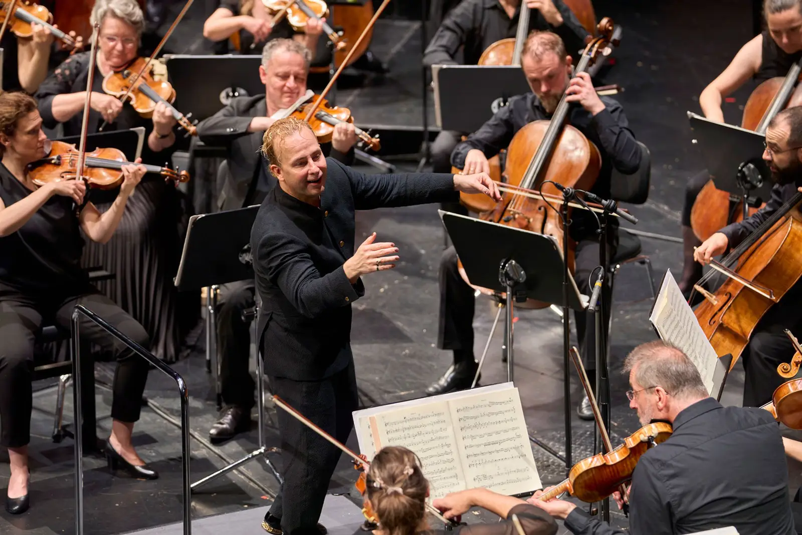 Dirigent dirigiert auf der Bühne ein Orchester und fühlt die Musik mit.