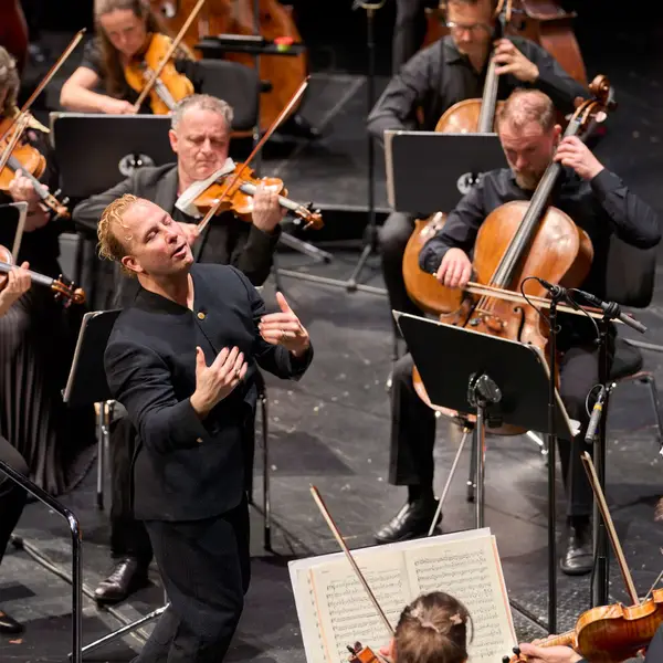 Dirigent auf der Bühne mit dem Orchester während des Konzert und fühlt die Musik mit.