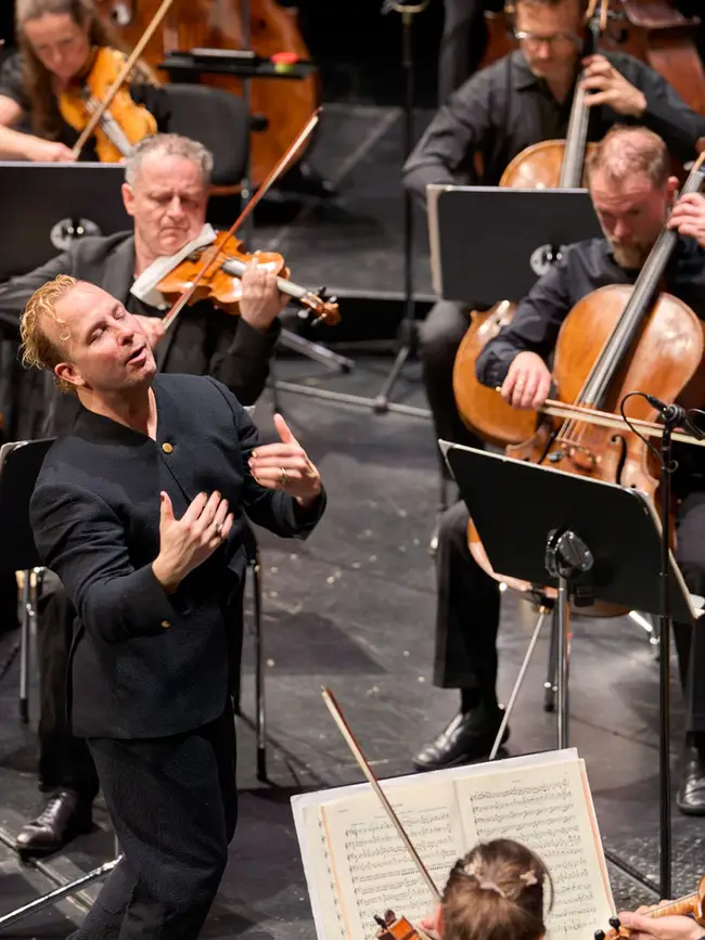 Dirigent auf der Bühne mit dem Orchester während des Konzert und fühlt die Musik mit.