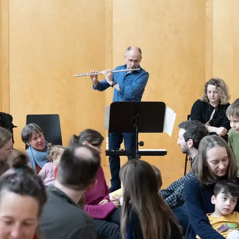 Ein Mann spielt Querflöte vor Kindern.
