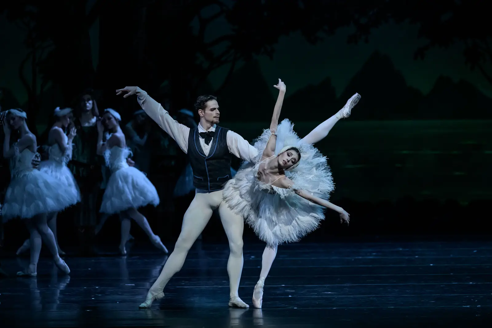 Un duo de ballet se produit sur scène. Le danseur porte une tenue formelle, la danseuse un tutu.