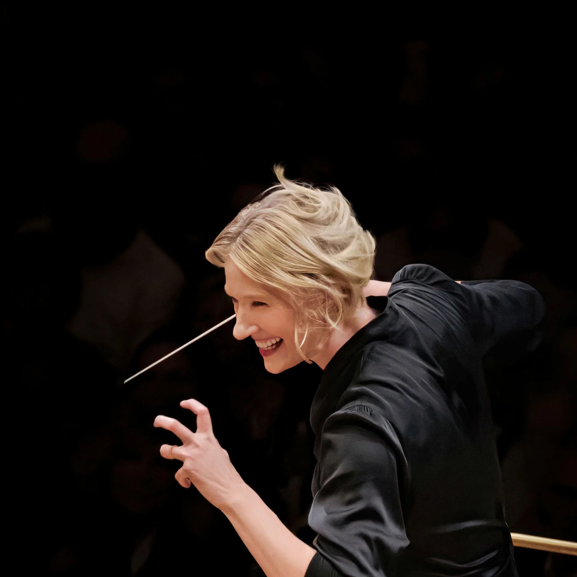 Die Dirigentin Joana Mallwitz mit kurzen, blonden Haaren dirigiert leidenschaftlich ein Orchester mit einem Taktstock in der Hand.