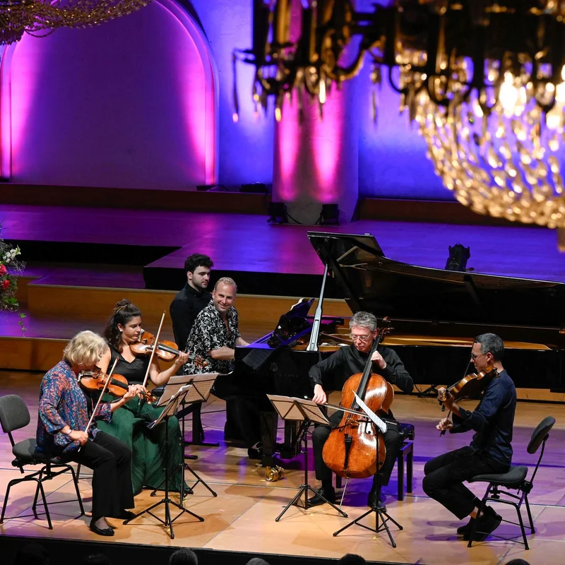 Yannick & Friends spielen auf einer Bühne unter einem großen Kronleuchter, umgeben von farbig beleuchteten Wänden und Blumendekorationen.