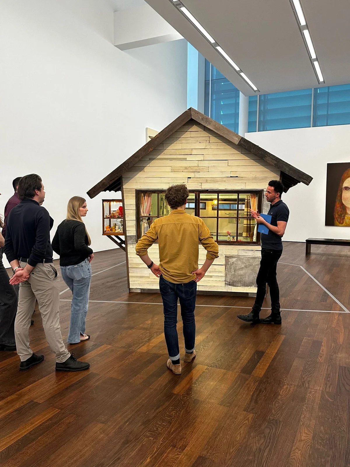 Eine Gruppe Menschen betrachtet ein Kunstwerk in Form eines kleinen Hauses in einem modernen Ausstellungsraum im Museum Frieder Burda.