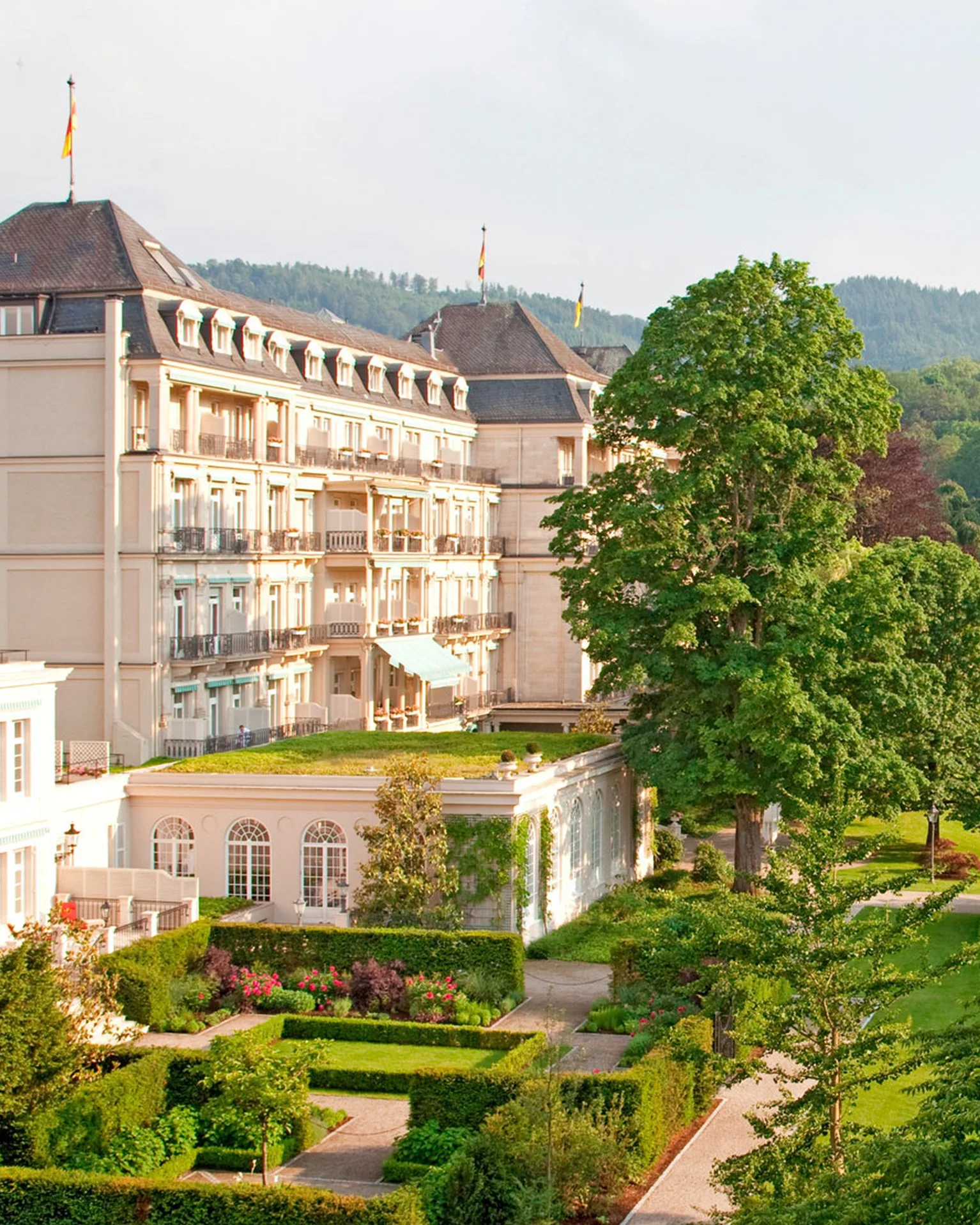 Ein elegantes Hotel mit historischer Architektur, umgeben von gepflegten Gärten und grüner Landschaft. Es liegt in einer idyllischen Umgebung.