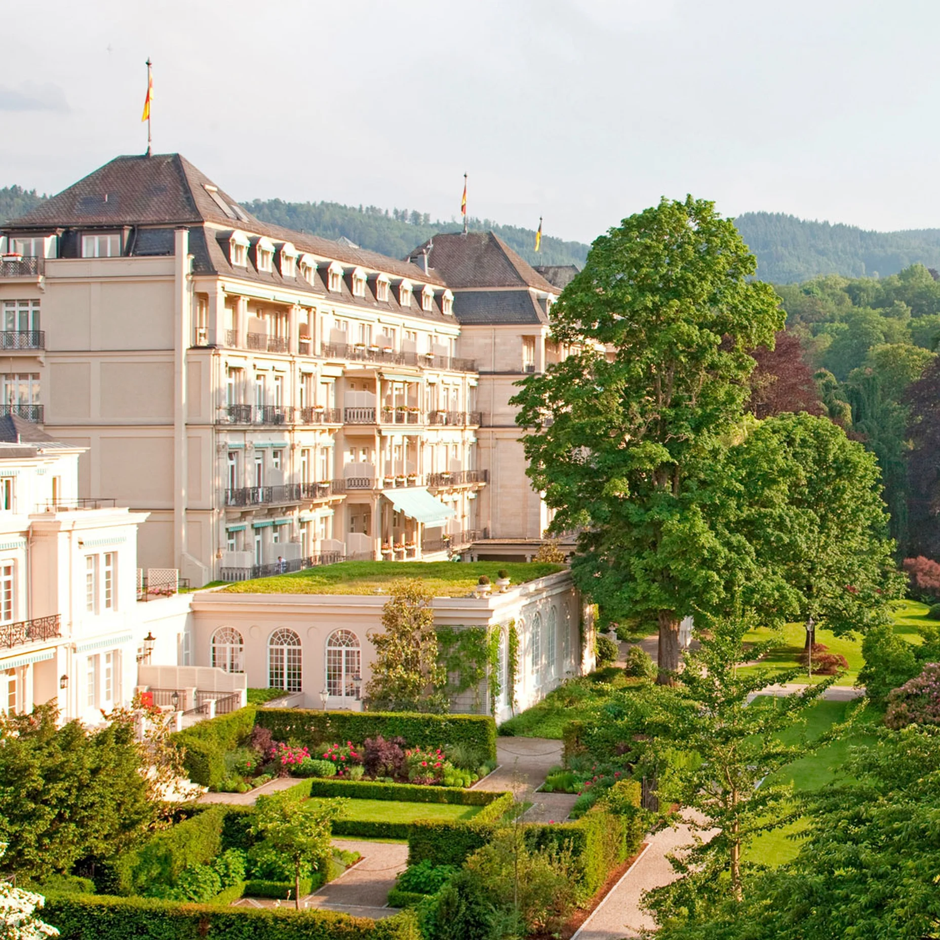 Ein elegantes Hotel mit historischer Architektur, umgeben von gepflegten Gärten und grüner Landschaft. Es liegt in einer idyllischen Umgebung.