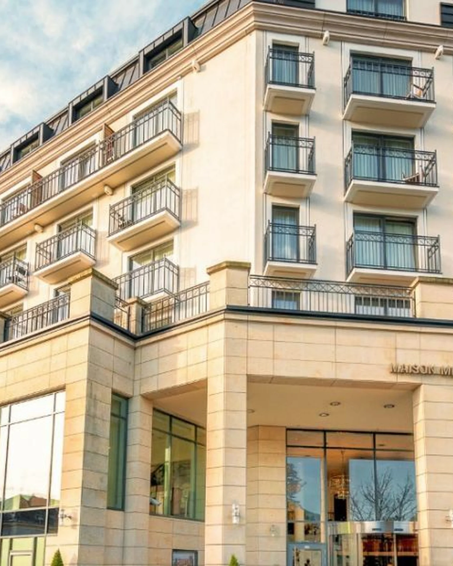 Ein modernes, mehrstöckiges Hotelgebäude mit Balkonen und großen Fenstern. Der Himmel ist klar mit einigen Wolken.