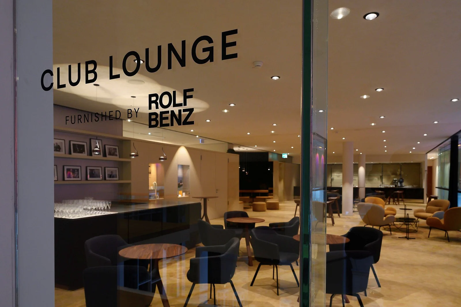 Eine stilvolle Club Lounge mit einer eleganten Einrichtung, darunter bequeme Stühle und Tische. Dezente Beleuchtung schafft eine gemütliche Atmosphäre.