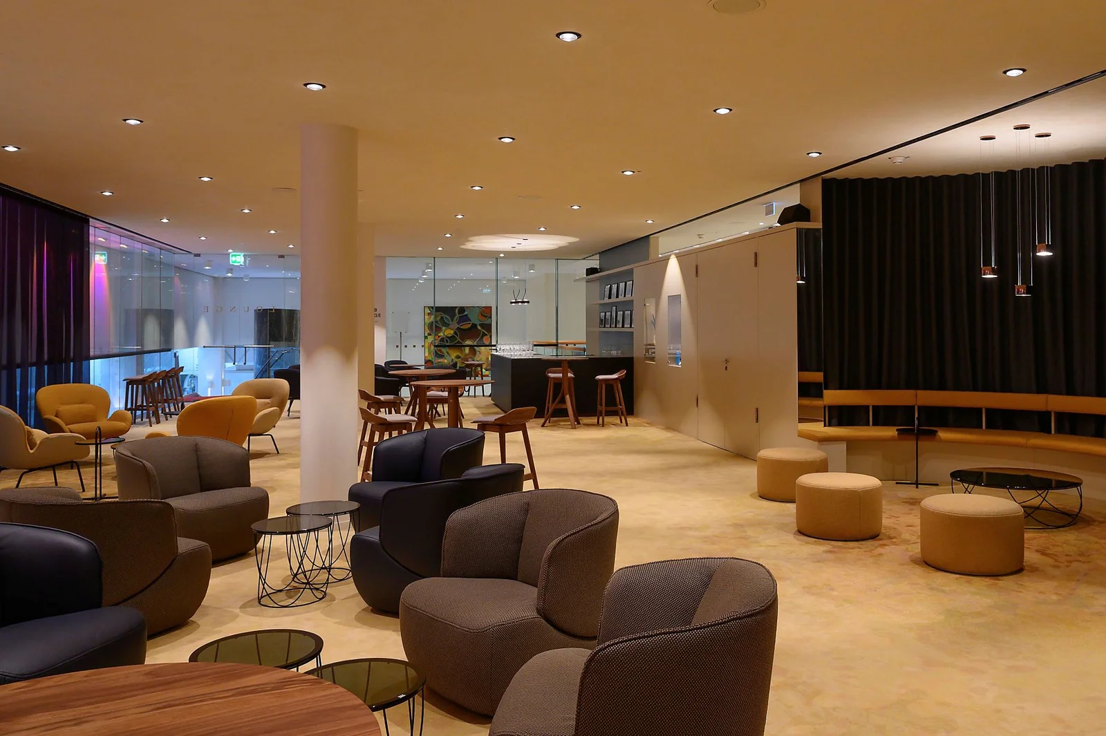 Ein modernes Lounge-Café mit stilvollen Möbeln, Tischen und gedämpfter Beleuchtung. Der Raum ist für Gäste vorbereitet.