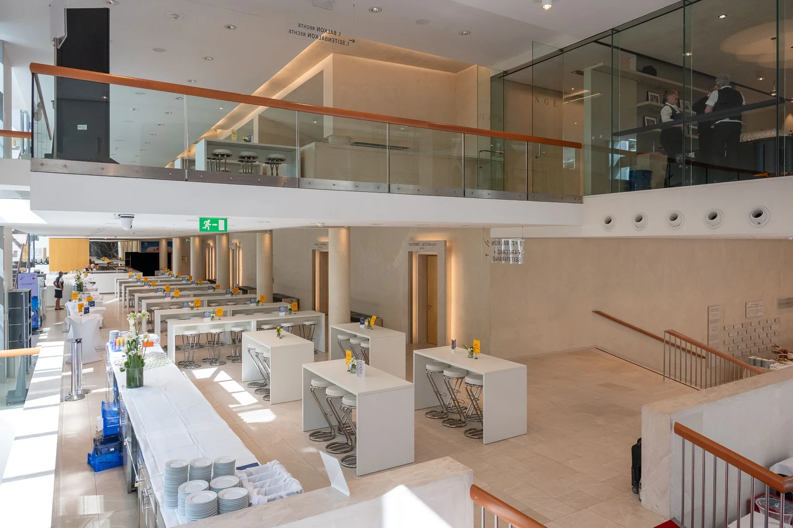 Das Foyer des Festspielhauses mit weißen Tischen, Glasbalustraden und hohen Decken, bereit für eine Konferenz oder ein Bankett.