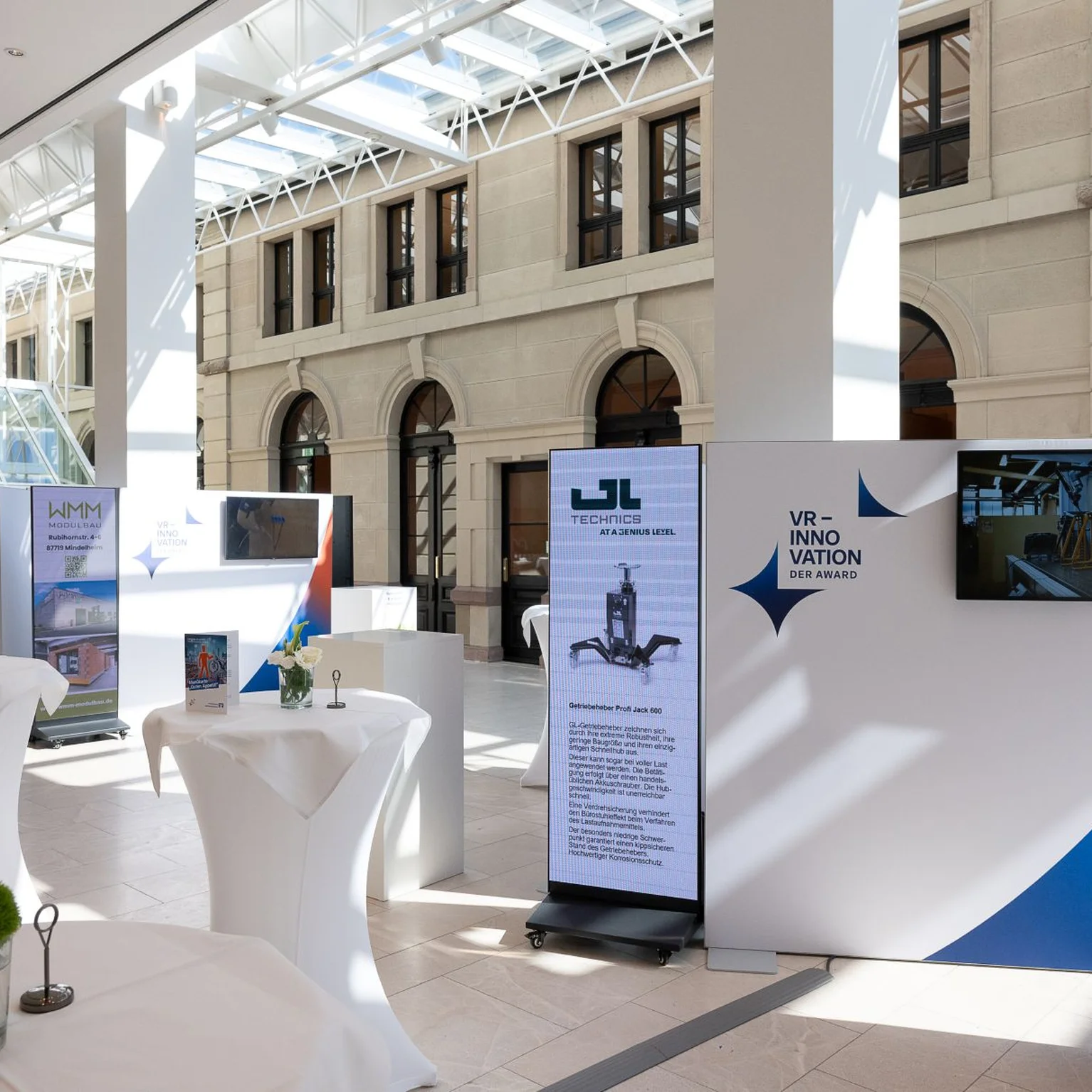 Das Foyer des Festspielhauses mit hohen Decken und natürlichem Licht. Verschiedene Displays und Tische sind im Raum angeordnet.