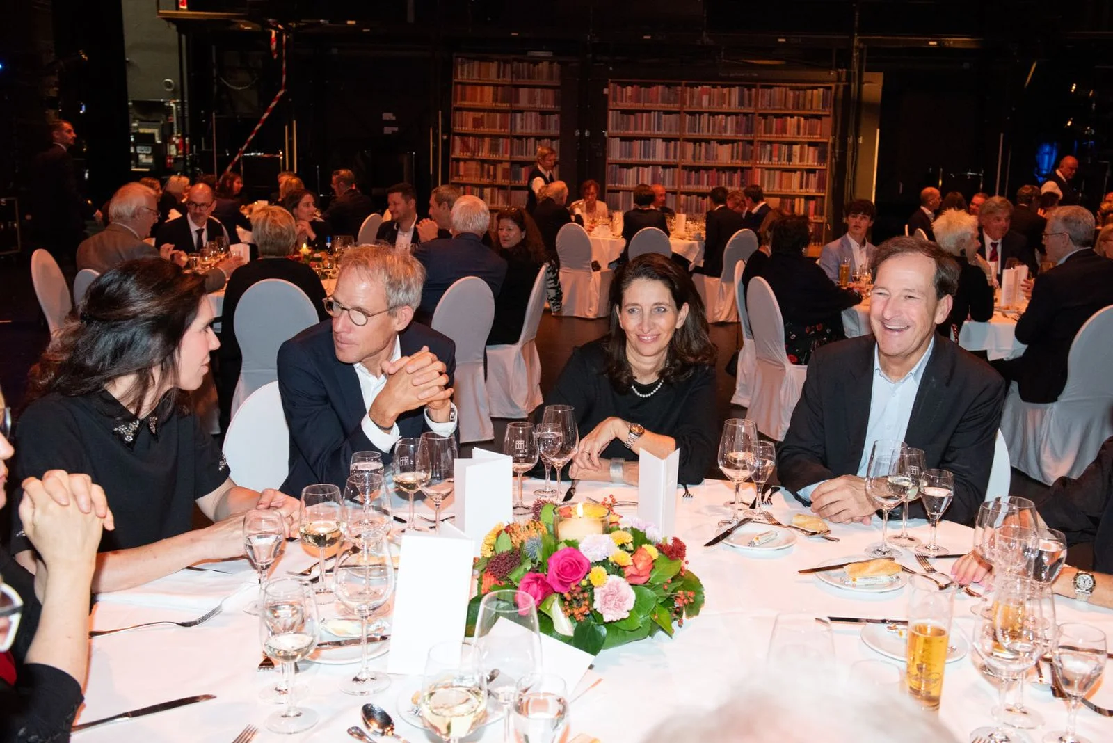 Menschen sitzen an einem festlich gedeckten Tisch bei einem eleganten Abendessen oder Gala.