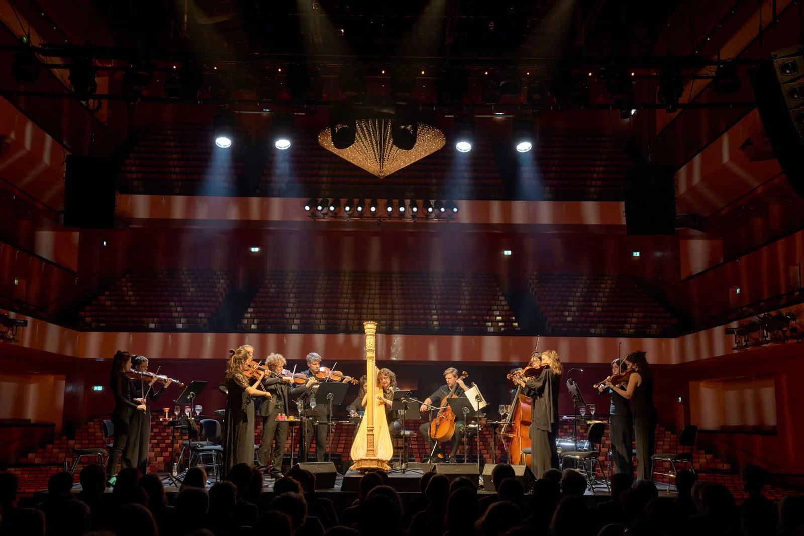 Das Ensemble spielt auf einem Podest, während das Publikum auf der Bühne sitzt und in den Saal blicken kann.
