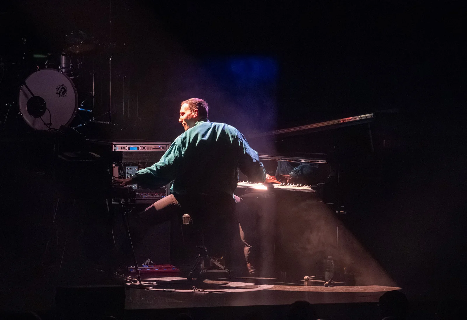 Künstler spielt am Klavier und wird erleuchtet von szenischem Licht auf der Bühne.
