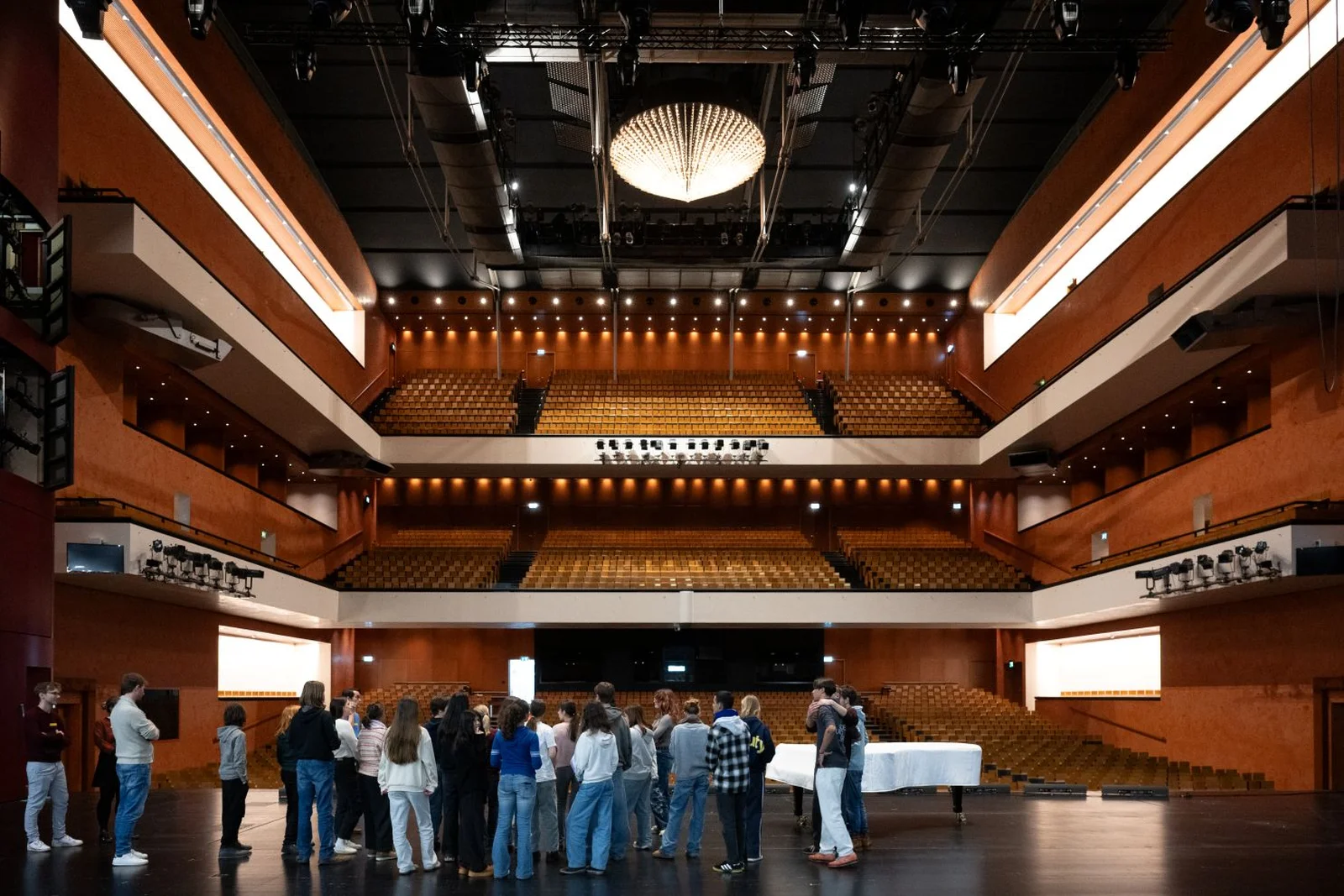 Eine Gruppe von Menschen steht auf der leeren Bühne mit Blick auf das geräumige und stilvolle Auditorium.